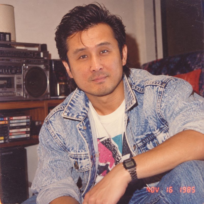 Dave, reimagined as a 1985 snapshot: acid-wash denim jacket, boombox and cassette tapes behind him, red-orange date stamp reading NOV 16 1985.